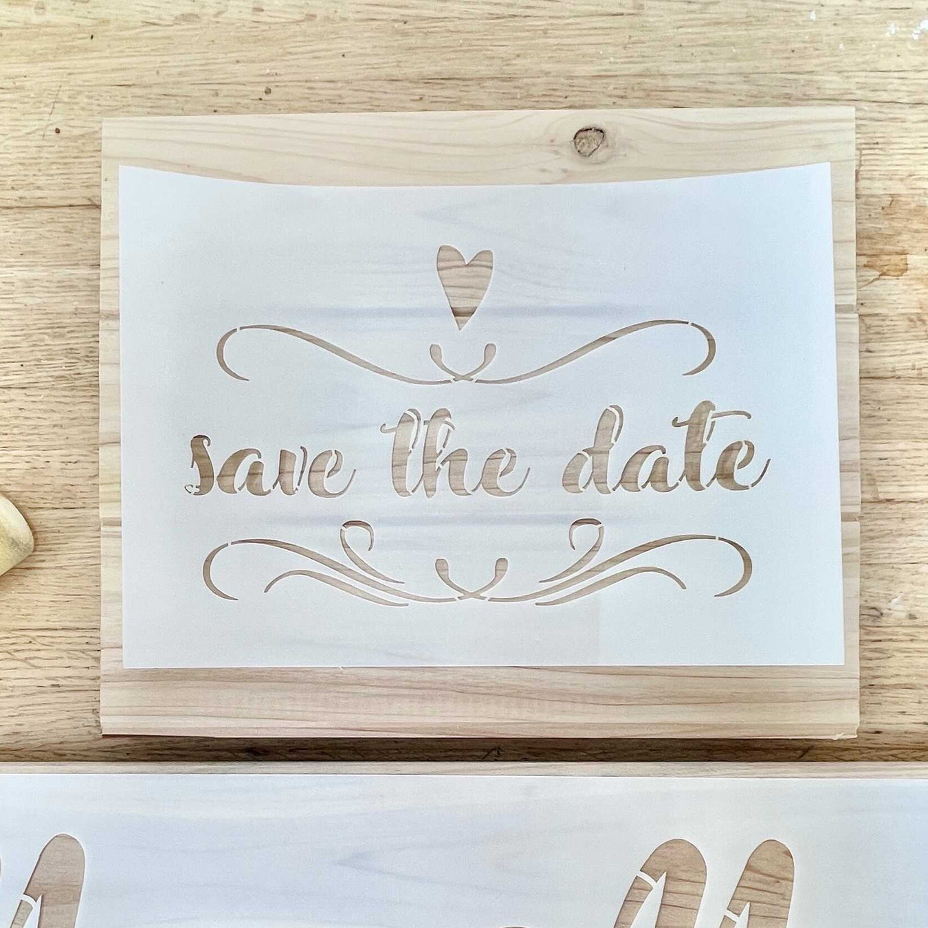 save the date words with heart and scrolls painted on wood using paint stencil