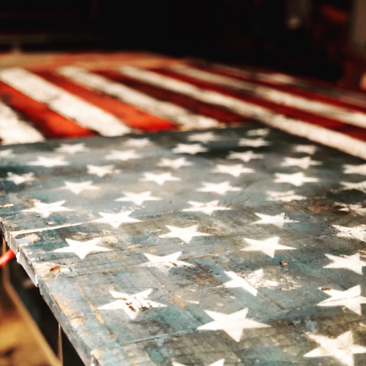 a close up image of American flag stars and stripes painted on a wooded table using stencil